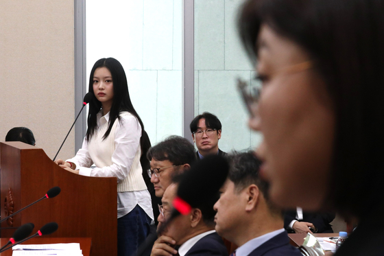 NewJeans member Hanni, left, stares at the head of her agency ADOR, Kim Ju-young, at the National Assembly on Oct. 15 [JOINT PRESS CORPS]
