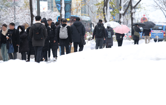 Commuters walk near Sejong-daero in Jung District, central Seoul, on Thursday as heavy snow continues for a second consecutive day. [YONHAP]
