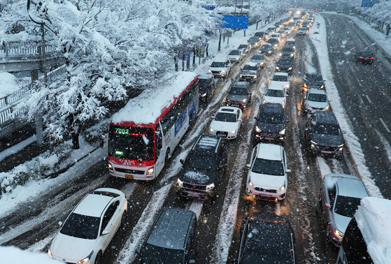 Vehicles clog the roads near Suwon World Cup Stadium in Gyeonggi as snow blankets the area on Thursday morning. [YONHAP]