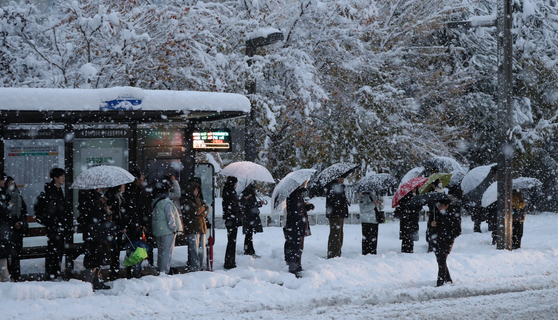 Commuters wait at a bus stop in Hwaseong, Gyeonggi, as snow falls on Thursday morning. [NEWS1]