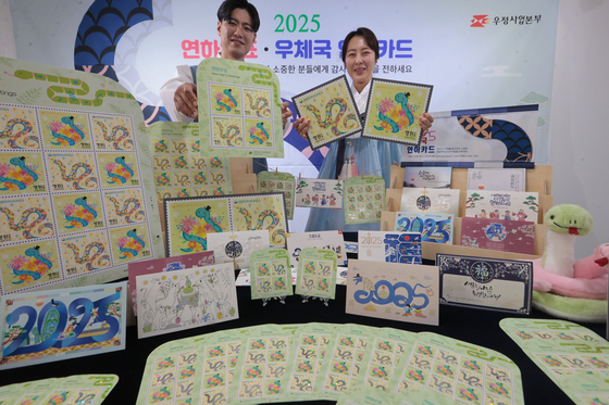 Korea Post employees introduce the 2025 editions of post cards and stamps for Year of the Blue Snake at the stamp museum in the service's headquarters in Jung District, central Seoul, on Monday. [YONHAP]