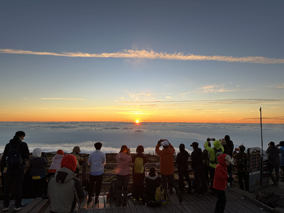 Hikers watch the sunrise on Oct. 13 at Mount Halla on Jeju Island. [YONHAP]