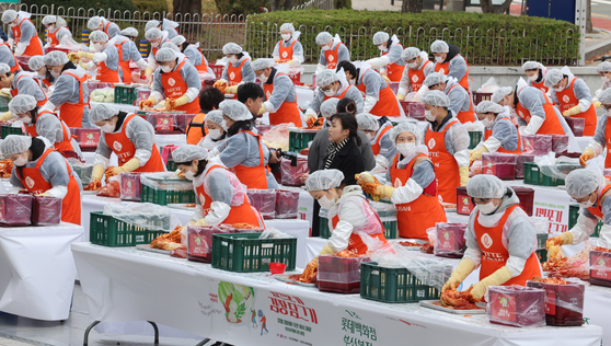 Employees of Lotte Group affiliates and civic groups make kimchi at Sajik Baseball Stadium in Busan on Tuesday. [YONHAP]