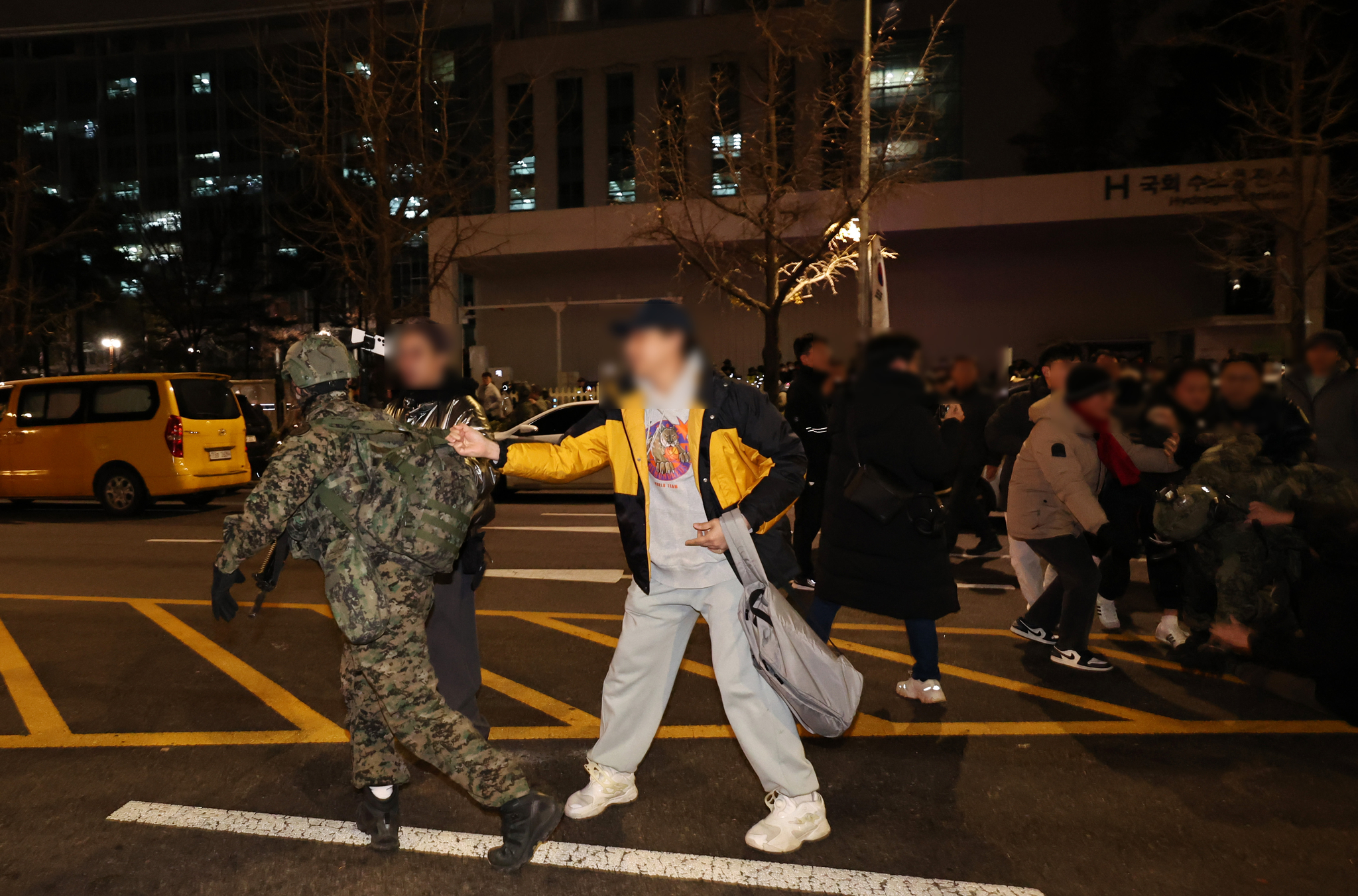A civilian stops an armed soldier attempting to enter parliamentary compound in western Seoul in early hours of Wednesday. Armored martial forces arrived at the National Assembly after President Yoon Suk Yeol declared martial law on Tuesday evening. [NEWS1]