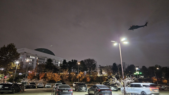 A military helicopter flies to the National Assembly building in western Seoul late Tuesday night after President Yoon Suk Yeol declared emergency martial law that day. [YONHAP]