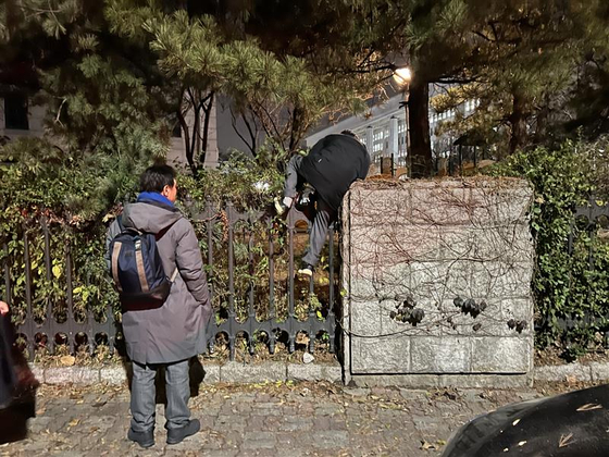 A citizen tries to climb over the National Assembly wall on Dec. 3 in western Seoul. [CHEA SARAH]