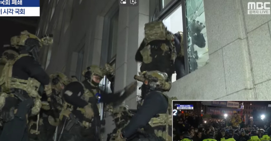 Military forces mobilized under Martial Law are spotted breaking windows of the National Assembly to get inside the chamber on Wednesday in footage aired by local broadcaster MBC. [SCREEN CAPTURE]