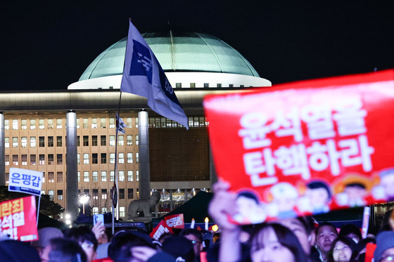 People participating in a candlelight march chant slogans urging the passage of the impeachment motion against President Yoon Suk Yeol on Saturday in front of the National Assembly in western Seoul. [KIM JONG-HO]