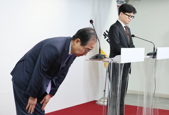 Prime Minister Han Duck-soo, left, bows during his public address with conservative People Power Party leader Han Dong-hoon in western Seoul on Sunday morning. [YONHAP] 
