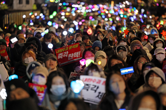 Protesters wave K-pop light sticks during a rally calling for President Yoon Suk Yeol's impeachment in Yeouido, Seoul, on Sunday. [YONHAP]