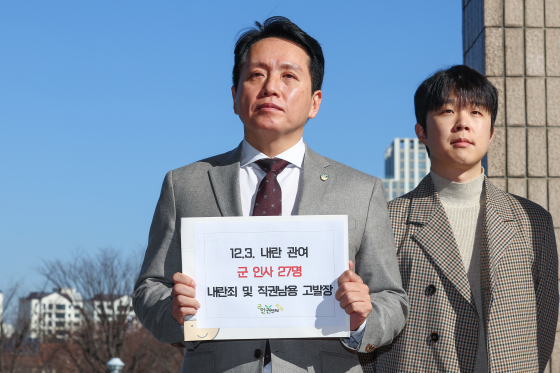 Lim Tae-hoon, head of the Center for Military Human Rights Korea, holds up his criminal report against 27 military officials for their alleged role in President Yoon Suk Yeol's imposition of martial law in front of the Corruption Investigation Office for High-Ranking Officials in Gwacheon, Gyeonggi, on Monday. [YONHAP]