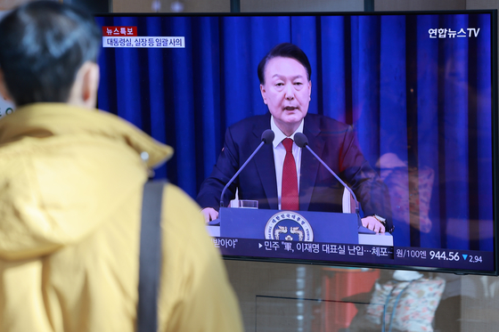 A person watches the news about President Yoon Suk Yeol's declaration and lift of the emergency martial law on Dec. 4 at Seoul Station in central Seoul. [YONHAP]