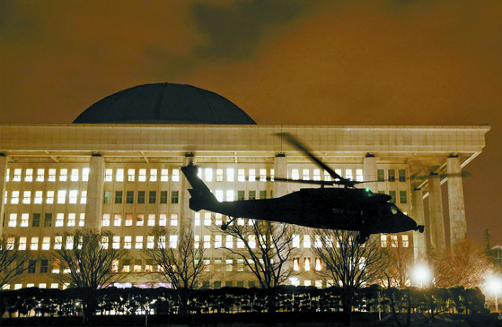 A military helicopter carrying martial law troops lands on the National Assembly grounds in Yeouido, western Seoul, early on Dec. 4, following President Yoon Suk Yeol's televised announcement of an emergency martial law just hours earlier. [JEON MIN-KYU]