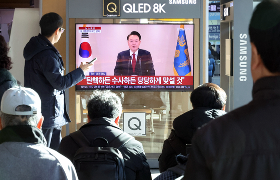 People watch President Yoon Suk Yeol's televised public address at Seoul Station, central Seoul, on Thursday. [YONHAP]