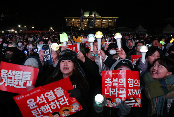 Protesters wave light sticks of various K-pop groups during a rally demanding President Yoon Suk Yeol's impeachment in front of the National Assembly in Yeouido District, western Seoul, on Saturday. [YONHAP] 