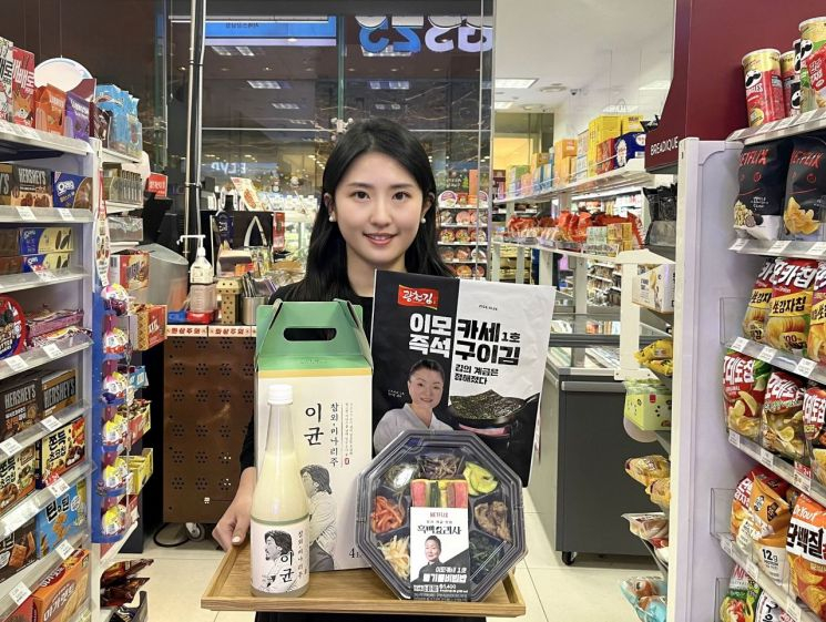 A woman holds Lee Kyun's Chamoe-Minari Makgeolli and Imokase's Grilled Gim, which began pre-orders on Dec. 16. [GS RETAIL] 