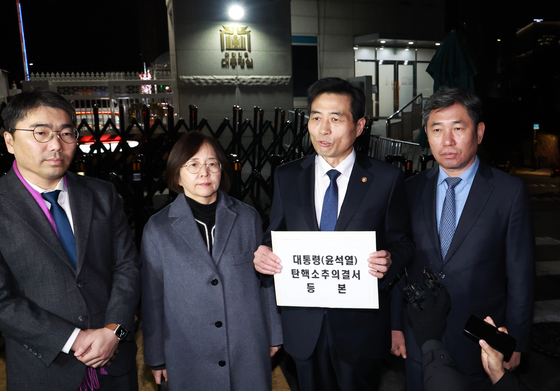 National Assembly Secretary General Kim Min-ki, second from the right, and other parliamentary officials deliver a copy of the impeachment resolution against President Yoon Suk Yeol to the Yongsan presidential office in central Seoul Saturday after it passed in the parliament earlier in the day. [YONHAP]