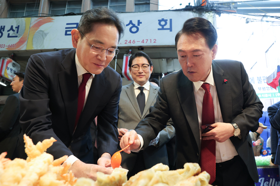 Samsung Electronics Executive Vice Chairman Lee Jae-yong, left, and President Yoon Suk Yeol taste eomuk, or fish cakes, at a traditional market in Busan on Dec. 6 last year. [PRESIDENTIAL OFFICE]