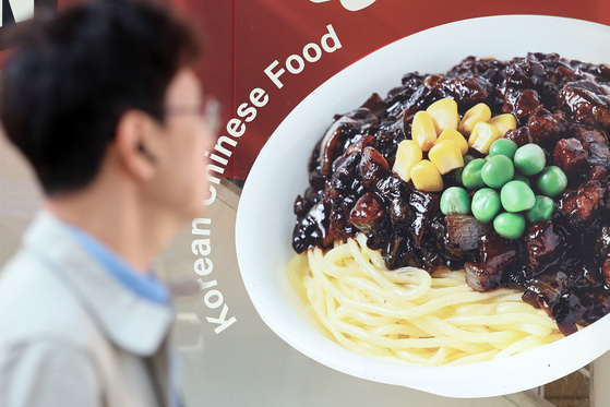 A pedestrian walks by a Chinese restaurant with a picture of jjajangmyeon (black bean noodles) in Seoul on Nov. 12. Jjajangmyeon prices rose by 5 percent in November compared to January of this year, according to the Korea Consumer Agency. [NEWS1]