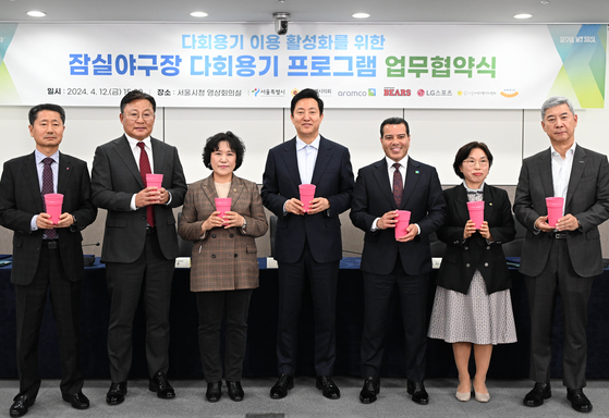 From left: Kim In-seok, CEO of LG Sports; Ko Young-seop, president of the Doosan Bears; Bong Yang-soon, head of the Environment and Water Resources Committee; Oh Se-hoon, mayor of Seoul; Khalid Radi, acting representative director of Aramco Asia Korea; Yoon Hye-yeon, chairman of the Seoul Association of Self-Sufficiency Promotion Centers; Shin Hee-ho, president of Amoje Food pose for a photo with reuseable cups at the 'Multi-use Plastic Food Tray Program' partnership agreement ceremony at Seoul City Hall. [SEOUL METROPOLITAN GOVERNMENT]