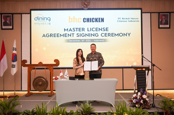 Dining Brands Group CEO Song Ho-seop, right, and Nachindo group CEO pose for a photo at a master license agreement signing ceremony on Monday. Chicken franchise BHC will open a shop in Jakarta under the agreement in the first half of 2025, marking the brand’s entry into the Indonesian market. [DINING BRANDS GROUP]