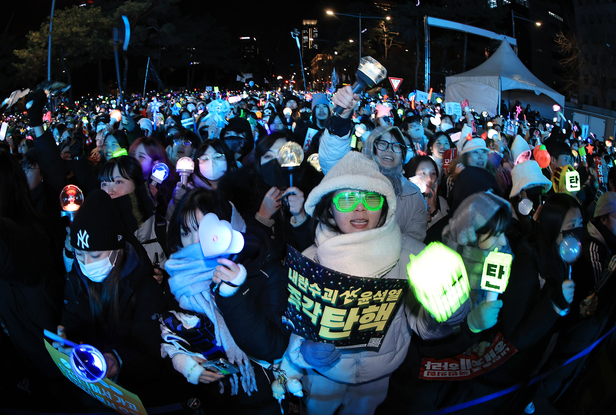 Protesters holding K-pop lightsticks in front of the National Assembly in western Seoul cheer and smile after the impeachment vote result was announced on Saturday. [NEWS1]