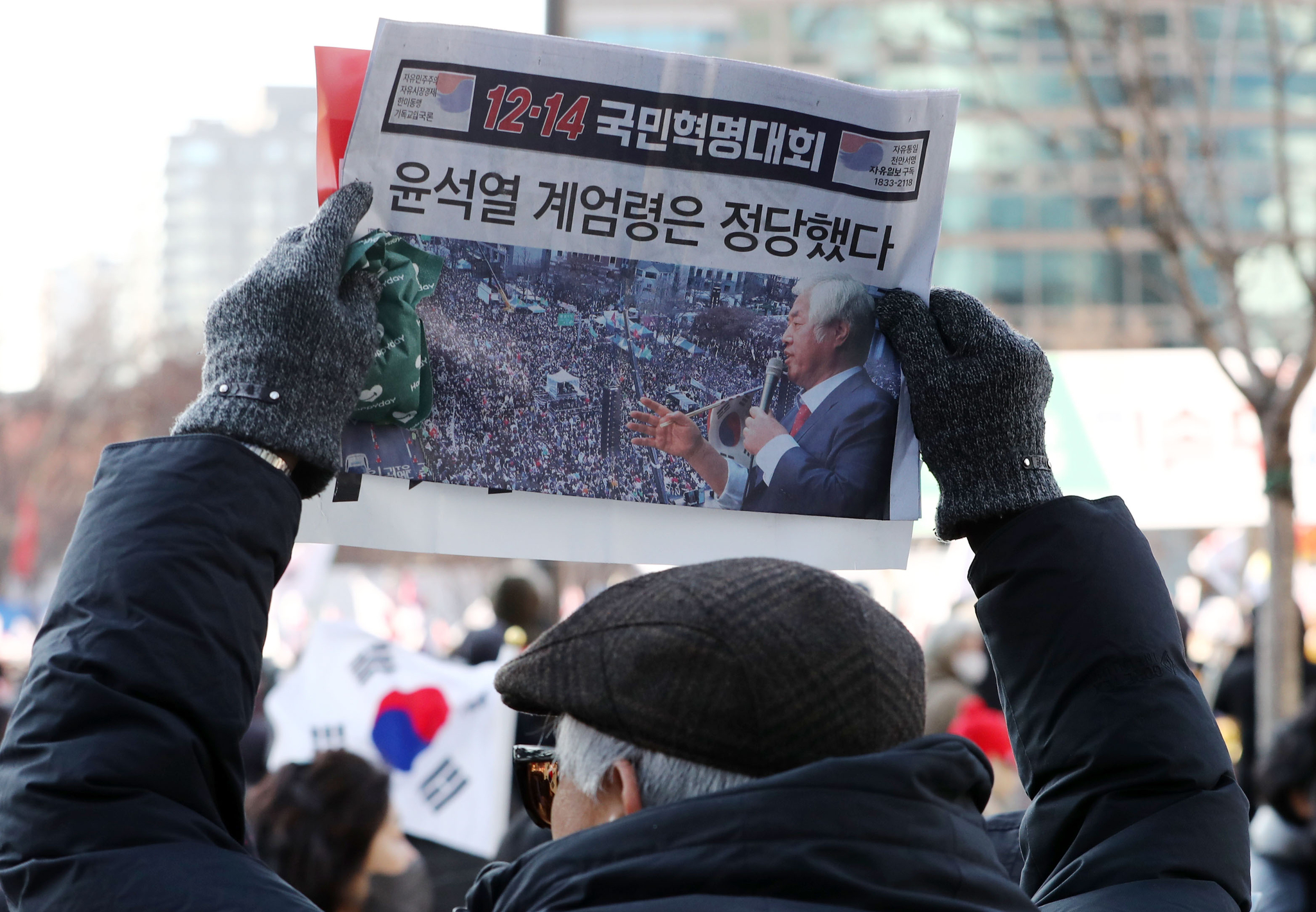 A protester from a conservative group holds a flyer reading ″President Yoon Suk Yeol's Martial law declaration was just″ during a rally supporting Yoon in central Seoul on Saturday. [NEWS1