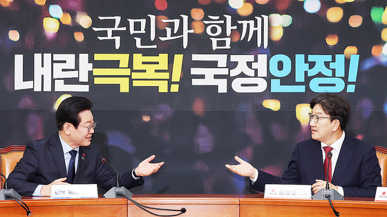 Democratic Party leader Lee Jae-myung, left, and People Power Party floor leader and acting chief Kweon Seong-dong gesture to each other during their first official meeting at the National Assembly in Yeouido, western Seoul, on Wednesday. [YONHAP]