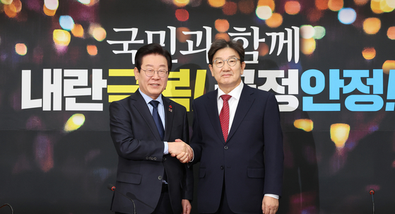 Democratic Party leader Lee Jae-myung, left, and People Power Party floor leader and acting chief Kweon Seong-dong pose for a photo during their first official meeting at the National Assembly in Yeouido, western Seoul, on Dec. 18. [YONHAP]