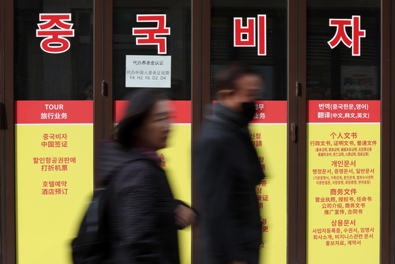 Pedestrians walk by a travel agency in Jung District, central Seoul, that specializes in Chinese visas on Dec. 1. [NEWS1]