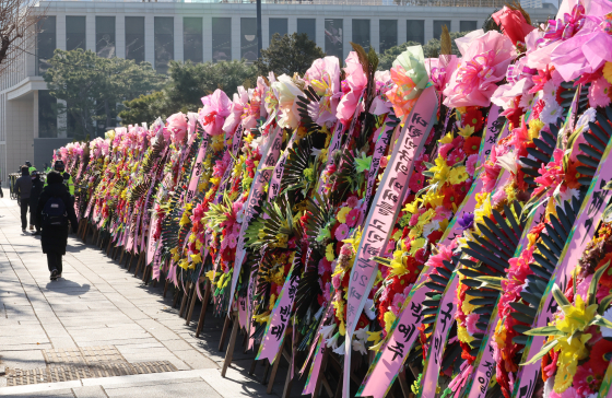 Floral wreaths with banners expressing support for President Yoon Suk Yeol line a street outside the Constitutional Court in Jongno District, central Seoul, on Dec. 19. [YONHAP]