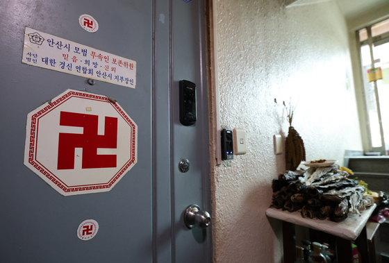 A symbol commonly associated with Buddhist temples and fortune tellers can be seen affixed to the front door of former Defense Intelligence Command chief Noh Sang-won's residence in Ansan, Gyeonggi, on Friday. A pile of dried fish, commonly used in shamanistic rituals, is on the right. [NEWS1]