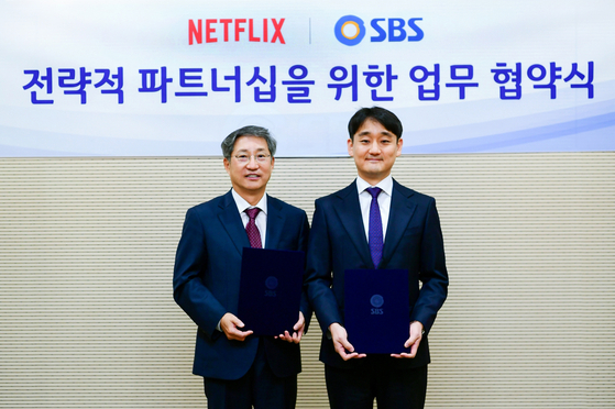 SBS CEO Bang Moon-shin, left, and Kang Dong-han, Netflix's vice president for Korean content, pose for a photo after signing a strategic business partnership on Friday. [SBS]