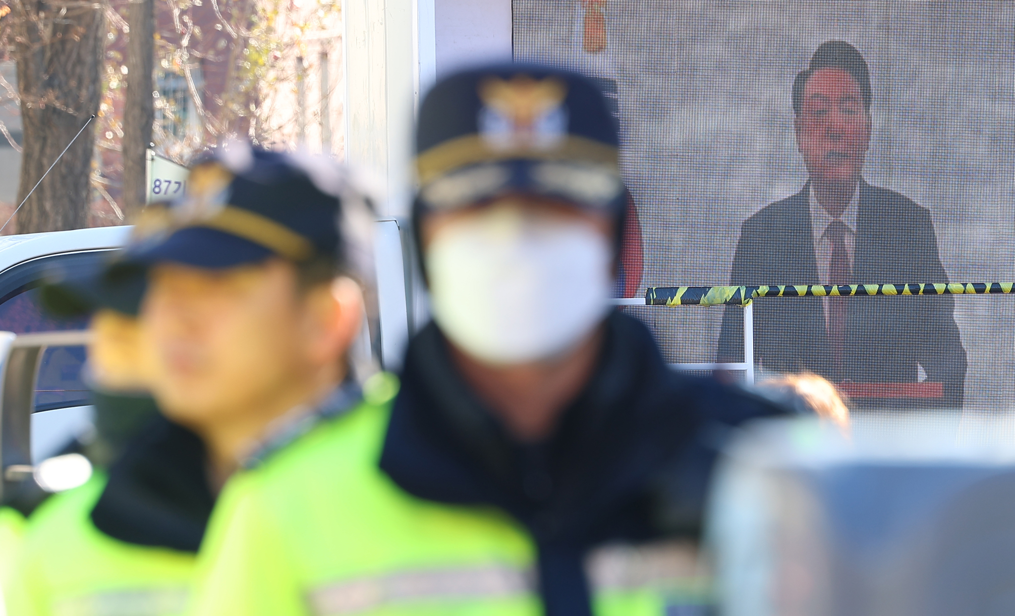 Police stand on guard outside President Yoon Suk Yeol's official residence in Yongsan District, central Seoul, on Dec. 24. A video of the president is broadcast on an outdoor screen mounted by his supporters behind the police officers, who were there to maintain a distance between dueling rallies for and against his impeachment. [YONHAP]