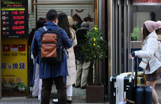 People stand in line at a currency exchange shop in the Myeong-dong area of Jung District, central Seoul, on Dec. 24. [YONHAP]