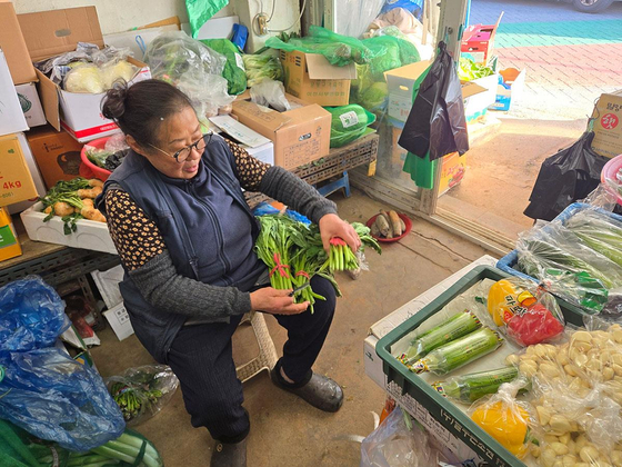 Han Cheon-hee, 75, who runs a small vegetable store in Yeomni-dong, Mapo District, central Seoul, arranges items in her store on Dec. 20. [YONHAP]