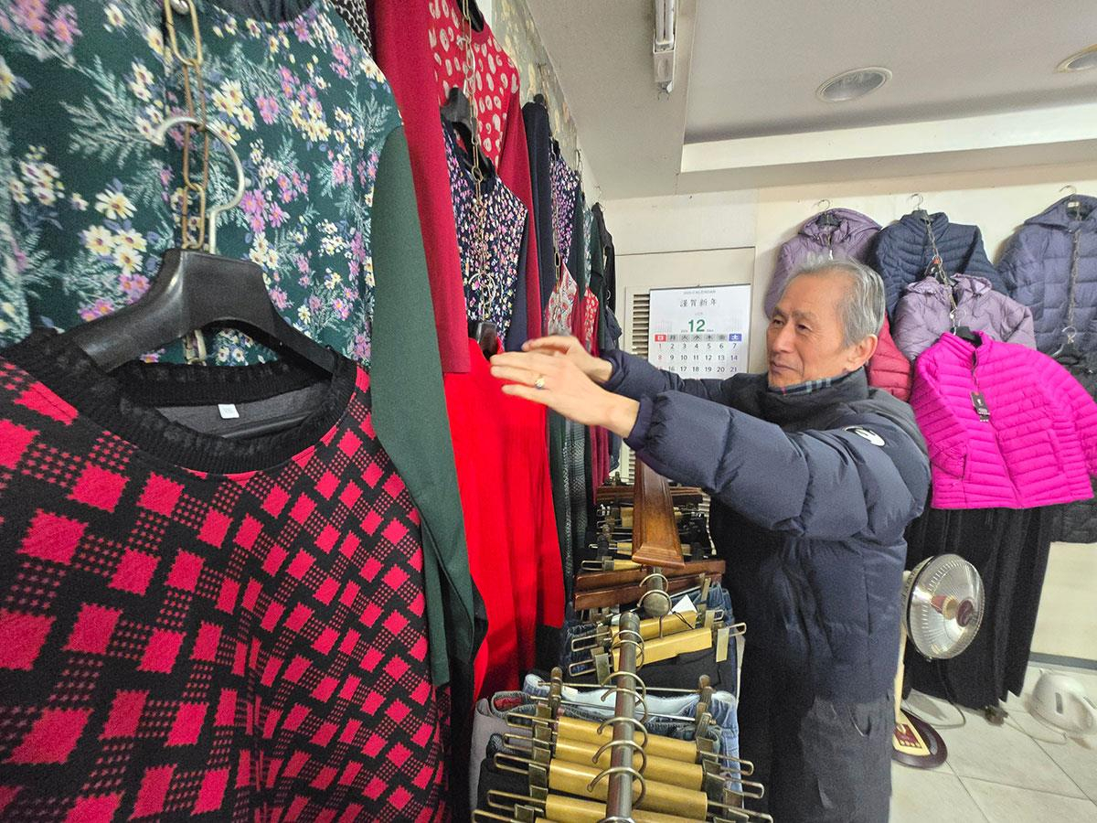 Kim Jin-ha, a 78-year-old clothing shop owner in Yeomni-dong, Mapo District, central Seoul, arranges a clothing display at his small neighborhood store on Dec. 20. [YONHAP]