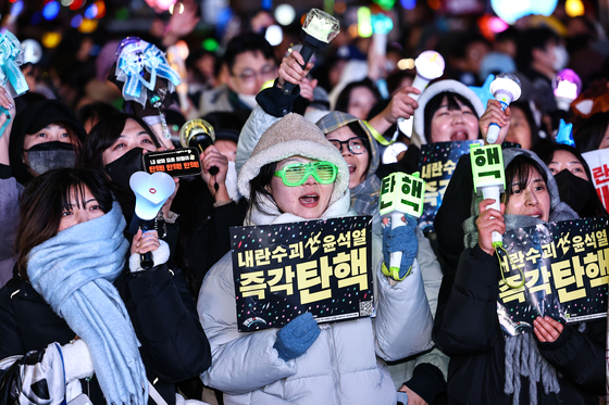Protesters cheer with light sticks and placards in a rally after the impeachment of President Yoon Suk Yeol was passed in parliament near the National Assembly in western Seoul on Dec. 14. [JOONGANG ILBO]