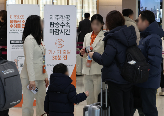 Passengers make inquiries for Jeju Air flights at Gimpo International Airport on Dec. 29 after a fatal airplane crash in Muan, South Jeolla. [YONHAP]