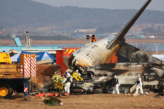 Emergency authorities survey the site of a plane crash at Muan International Airport on Dec. 29. [YONHAP] 