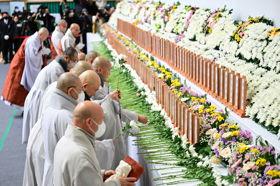 Monks place wreaths at a memorial altar set up in Muan Sports Complex in Muan, South Jeolla, for the victims of Sunday’s Jeju Air crash, on Monday. [JOONGANG ILBO] 