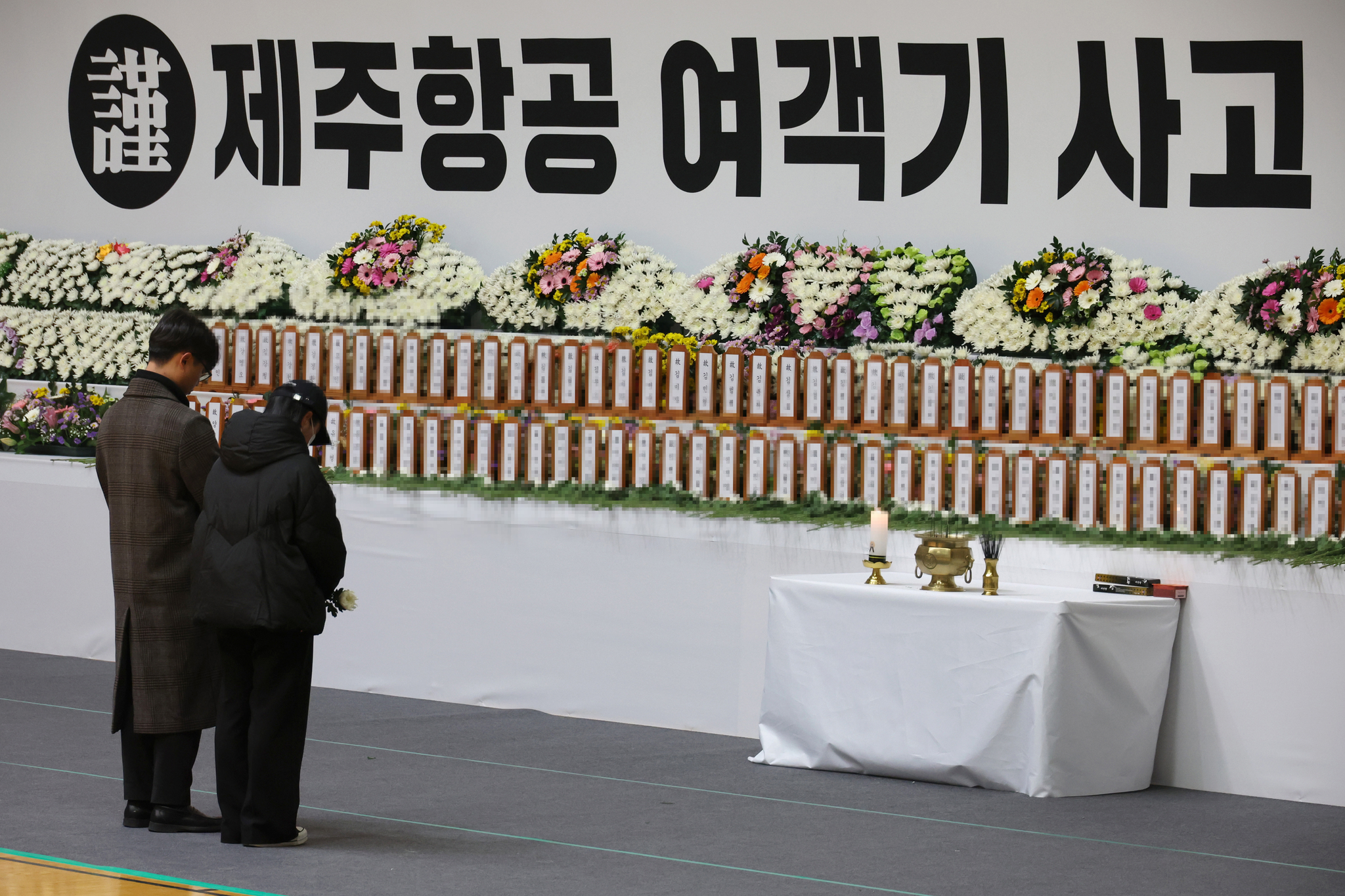 Bereaved families of the victims of Sunday’s Jeju Air plane crash pay a silent tribute at a memorial altar set up in Muan Sports Complex in Muan, South Jeolla, on Monday. [JOONGANG ILBO] 
