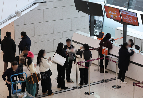 Passengers wait in line to ask questions about boarding at Jeju Air's counter at Gimpo International Airport in Gangseo District, western Seoul, on Dec. 30. [YONHAP]