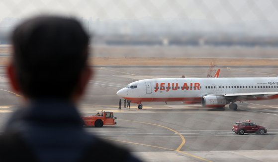 A man watches a Jeju Air plane preparing to take off at Gimpo International Airport in Gangseo District, western Seoul, on Dec. 30. [YONHAP]