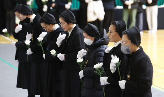 Nuns pray at a memorial altar set up in Muan Sports Complex in Muan, South Jeolla, for the victims of Sunday’s Jeju Air crash, on Monday. [JOONGANG ILBO] 