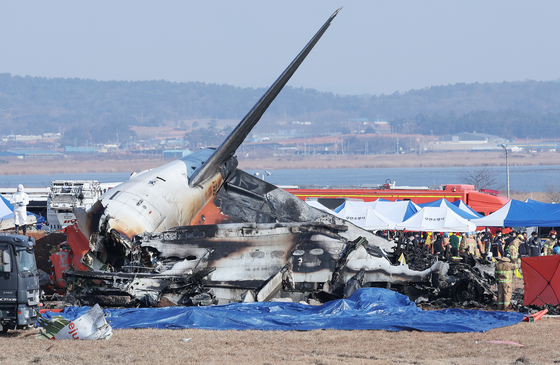 Emergency authorities survey the site of a plane crash at Muan International Airport on Dec. 29. [YONHAP]
