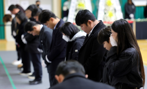 Bereaved families of the victims of Sunday’s Jeju Air crash pay respects at a memorial altar set up in Muan Sports Complex in Muan, South Jeolla, on Monday. [JOONGANG ILBO] 
