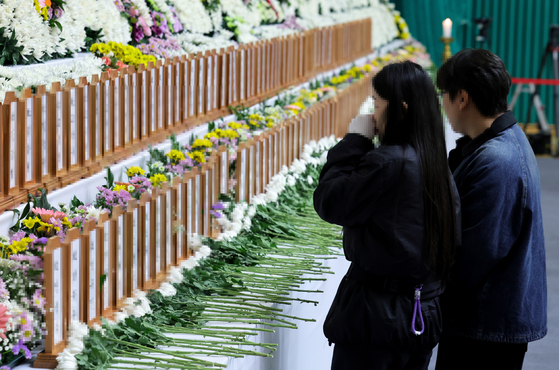 Bereaved families of the victims of Sunday’s Jeju Air crash weep at a memorial altar set up in Muan Sports omplex in Muan, South Jeolla, on Monday. [JOONGANG ILBO] 