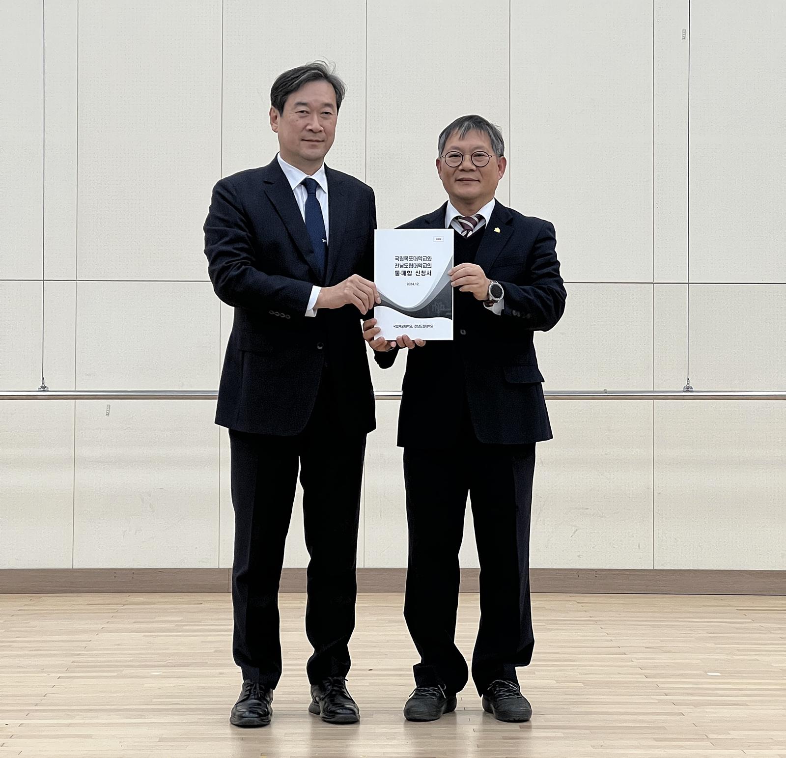 Mokpo National University President Song Ha-cheol, left, poses for a photo with Jeonnam State University Acting President Jang Heon-beom on Dec. 27 while holding the merger plan the universities submitted to the Ministry of Education. [MOKPO NATIONAL UNIVERSITY]
