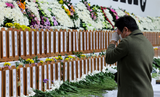 A bereaved family member of the victims of Sunday’s Jeju Air crash sheds tears at a memorial altar set up in Muan Sports Complex in Muan, South Jeolla, on Monday. [JOONGANG ILBO] 